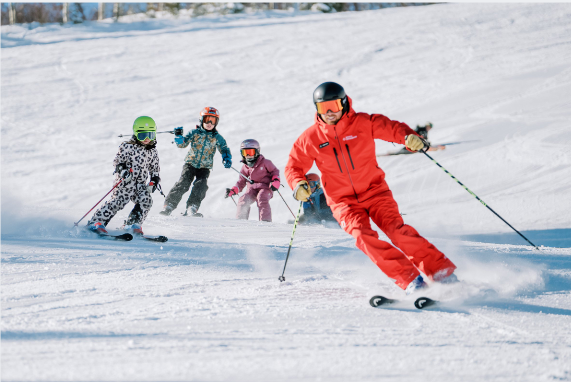 Instructor dando una clase de ski a niños